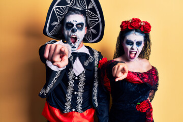 Obraz premium Young couple wearing mexican day of the dead costume over yellow pointing displeased and frustrated to the camera, angry and furious with you