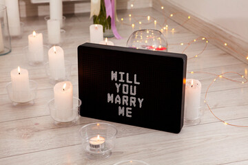 Will you marry me. The inscription on the card to a friend. Greeting for a wedding proposal with candles background