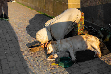 A woman kneels next to a sleeping dog and a puppy begging for alms from passers-by on the Charles...