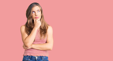 Beautiful caucasian young woman wearing casual clothes with hand on chin thinking about question, pensive expression. smiling with thoughtful face. doubt concept.