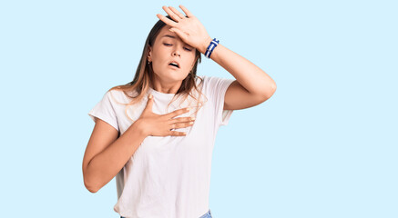 Beautiful caucasian woman wearing casual white tshirt touching forehead for illness and fever, flu and cold, virus sick