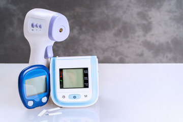 Remote thermometer, blood glucose meter and wrist blood pressure monitor on table with copy space....