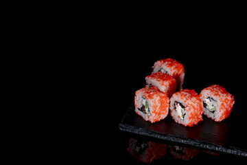 Philadelphia roll with salmon, cheese and cucumber on a black background with reflection. Sushi Philadelphia
