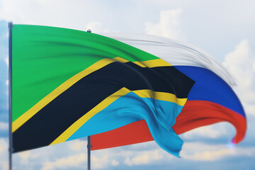 Waving Russian flag and flag of Tanzania. Closeup view, 3D illustration.