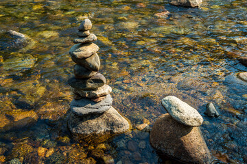 Fototapeta na wymiar balanced Zen stones stacked rock art in flowing water of mountain stream