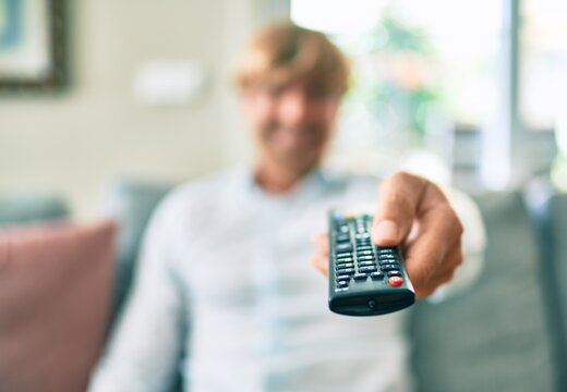 Close up of middle age handsome caucasian man using tv control