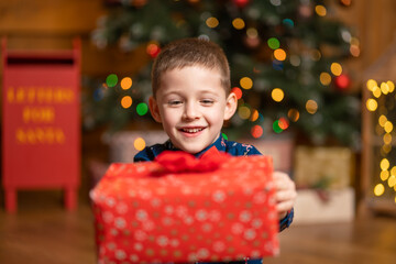 Fototapeta na wymiar Christmas fabulous, little boy holding a big red box with a present from Santa