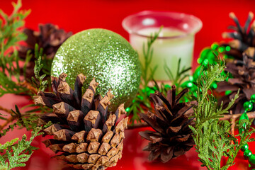 Festive composition of cones and Christmas balls on red background for design and greeting cards.