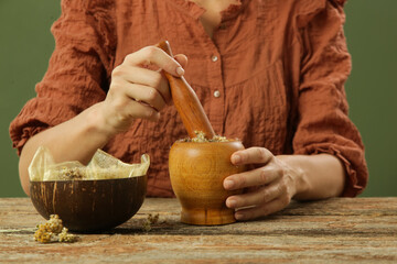 Woman preparing natural medicines with mortar and pestle. Process of making natural cosmetic or...