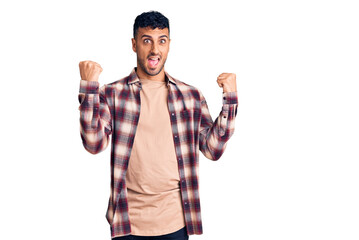 Fototapeta premium Young hispanic man wearing casual clothes screaming proud, celebrating victory and success very excited with raised arms