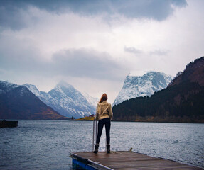 Norway - Beautiful girl gazing towards mountain range by fjord in Sæbø