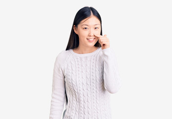 Young beautiful chinese woman wearing casual sweater pointing with hand finger to face and nose, smiling cheerful. beauty concept