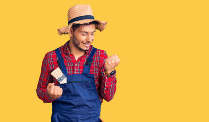 Handsome latin american young man weaing handyman uniform celebrating surprised and amazed for success with arms raised and eyes closed. winner concept.