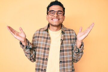 Young handsome hispanic man wearing casual clothes and glasses celebrating victory with happy smile...