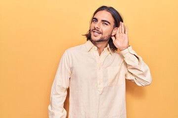 Young handsome man wearing business clothes smiling with hand over ear listening an hearing to rumor or gossip. deafness concept.