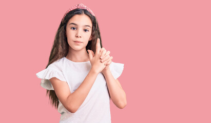 Cute hispanic child girl wearing casual white tshirt holding symbolic gun with hand gesture, playing killing shooting weapons, angry face