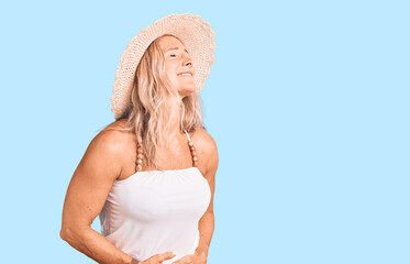 Middle age fit blonde woman wearing summer hat with hand on stomach because nausea, painful disease feeling unwell. ache concept.