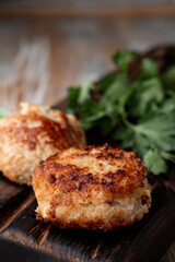 Golden roasted russian meat patties on a dark wooden board with herbs around, close up, appetizing photo