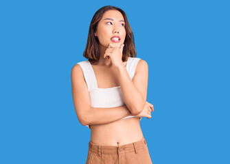 Fototapeta premium Young beautiful chinese girl wearing casual clothes with hand on chin thinking about question, pensive expression. smiling with thoughtful face. doubt concept.