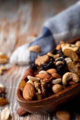 Fototapeta na wymiar Nut mix in a wooden bowl on a light rustic wooden table, close up, selective focus, catalogue photo