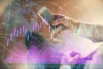 Double exposure of man's hands holding and using a digital device and forex graph drawing. Financial market concept.