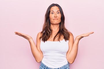 Young beautiful brunette woman wearing casual sleeveless t-shirt over white background clueless and...