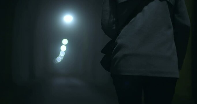 A woman walks alone on a dark alley at nighttime, The Netherlands.
