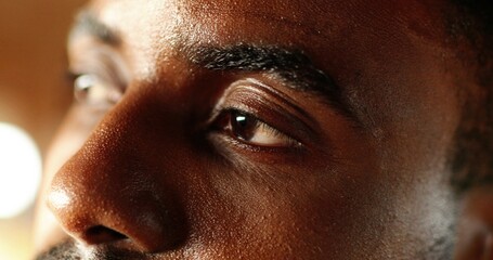 Close up of young face of happy African American man with sweat drops on skin looking at side....
