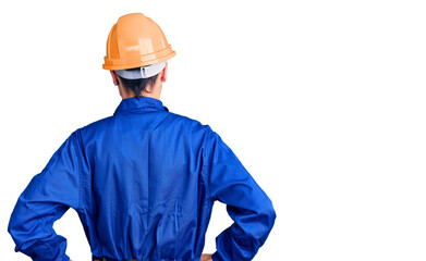 Young hispanic man wearing worker uniform standing backwards looking away with arms on body
