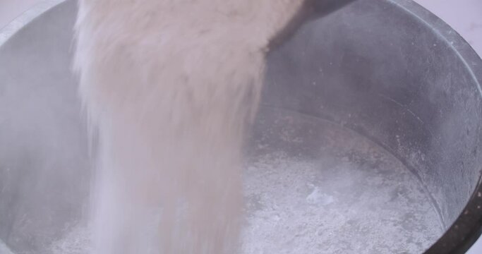 Closeup shot of dry plaster being poured into a mixing bucket with water.