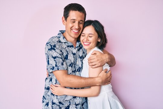 Beautiful couple wearing casual clothes hugging oneself happy and positive, smiling confident. self love and self care
