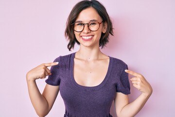 Young beautiful woman wearing casual clothes and glasses looking confident with smile on face,...