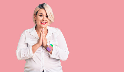 Young blonde plus size woman wearing casual shirt praying with hands together asking for forgiveness smiling confident.