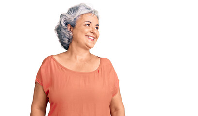 Senior woman with gray hair wearing orange tshirt looking away to side with smile on face, natural expression. laughing confident.