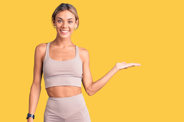 Beautiful caucasian woman wearing sportswear smiling cheerful presenting and pointing with palm of hand looking at the camera.