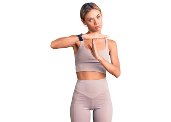 Beautiful caucasian woman wearing sportswear doing time out gesture with hands, frustrated and serious face