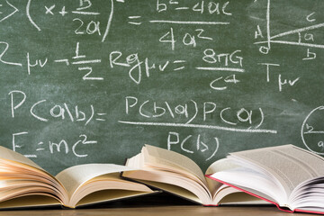 Open books against green chalkboard, close up