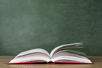 Open book against green chalkboard, close up