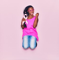 Young beautiful african american woman wearing glasses smiling happy. Jumping with smile on face...