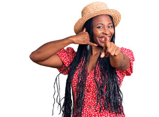 Young african american woman wearing summer hat smiling doing talking on the telephone gesture and...
