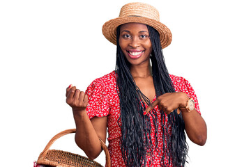 Young african american woman wearing summer hat and holding picnic wicker basket with bread smiling happy pointing with hand and finger