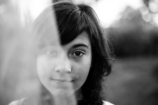 Close-up portrait of teen girl looking through the tulle. Black and white photography.