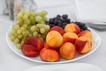 Peaches and grapes are on a platter