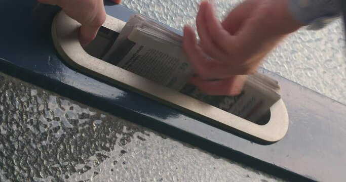 Rotterdam, The Netherlands - September 01 2017: Closeup shot of a home mailbox receiving a newspaper.