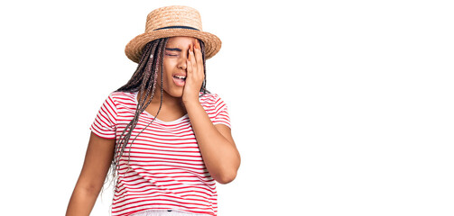 Obraz na płótnie Canvas Young african american woman with braids wearing summer hat yawning tired covering half face, eye and mouth with hand. face hurts in pain.
