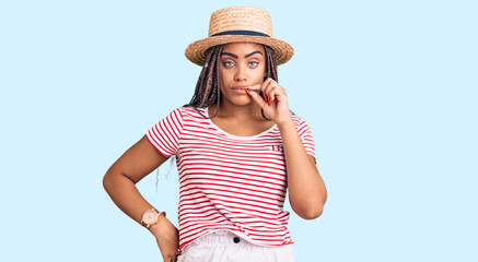 Obraz na płótnie Canvas Young african american woman with braids wearing summer hat mouth and lips shut as zip with fingers. secret and silent, taboo talking