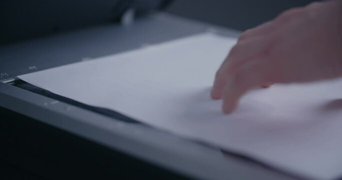 A person scans a document on an office scanner.