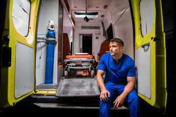 Corpsman in a blue uniform sitting in an ambulance car and thinking. © Anna Kosolapova