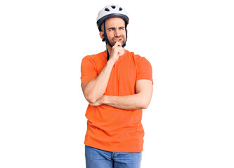 Young handsome man wearing bike helmet serious face thinking about question with hand on chin, thoughtful about confusing idea