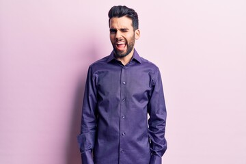 Young handsome man with beard wearing casual shirt winking looking at the camera with sexy expression, cheerful and happy face.